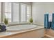 Bathroom featuring an oval soaking tub, shuttered windows, and tiled surround at 5949 225Th E St, Bradenton, FL 34211