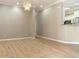 Open-plan living room featuring light wood-look flooring, neutral walls and a modern chandelier at 5949 225Th E St, Bradenton, FL 34211