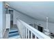 Hallway with white railing overlooking a living area, featuring blue striped rug on wood-look floors at 767 Pine Run Dr, Osprey, FL 34229