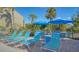 Relaxing pool area featuring lounge chairs with blue umbrellas and lush landscaping in a beautiful outdoor setting at 767 Pine Run Dr, Osprey, FL 34229