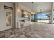 A view of the outdoor kitchen featuring stainless steel appliances and grey brick pavers overlooking the serene lake at 9241 Starry Night Ave, Sarasota, FL 34241