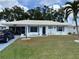 Charming home featuring a white exterior, white tile roof, blue shutters, and a well-maintained lawn at 1007 Pussywillow Ln, Bradenton, FL 34208