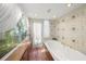 Bathroom featuring a tub, white tiling with decorative accents, and window with view of trees at 107 Nippino W Trl, Nokomis, FL 34275