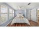 Relaxing bedroom with wood floors, soft blue walls, shuttered windows, and a cozy inviting bed at 107 Nippino W Trl, Nokomis, FL 34275