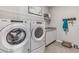 This laundry room includes a modern washer and dryer set with overhead storage and a pet bed at 10713 Tippecanoe Pl, Parrish, FL 34219