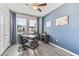 This is a home office with a desk, two chairs, and gray wood flooring with a blue accent wall at 10717 Tippecanoe Pl, Parrish, FL 34219