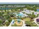 An aerial view shows community amenities, including a playground, pool, and clubhouse near a tranquil lake at 11021 Blue Magnolia Ln, Parrish, FL 34219
