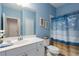 Well-lit bathroom with blue walls, a white vanity, and a shower with a coastal-themed curtain at 11021 Blue Magnolia Ln, Parrish, FL 34219