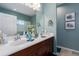 Bathroom featuring double sinks, a large mirror, and stylish decor with blue walls at 11021 Blue Magnolia Ln, Parrish, FL 34219
