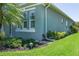 Landscaped exterior view with well-maintained lawn, mature plantings, and side-facing windows at 11021 Blue Magnolia Ln, Parrish, FL 34219