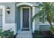 An inviting front entrance features a stylish black door, lush greenery, and decorative exterior lighting at 11021 Blue Magnolia Ln, Parrish, FL 34219