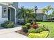 Beautifully landscaped front yard features a well-manicured lawn, colorful flower beds, and lush tropical foliage at 11021 Blue Magnolia Ln, Parrish, FL 34219