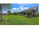 Expansive backyard featuring lush green grass, screened-in lanai, and a scenic water view at 11176 Roseate Ct, Sarasota, FL 34238