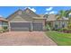 This house features a brick driveway, a two-car garage, manicured lawn, and tropical plants at 11176 Roseate Ct, Sarasota, FL 34238