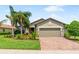 Charming single-story home with well-manicured lawn, lush landscaping, and a brick-paved driveway at 11214 Sandhill Preserve Dr, Sarasota, FL 34238