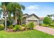 Charming single-story home with well-manicured lawn, lush landscaping, and a brick-paved driveway at 11214 Sandhill Preserve Dr, Sarasota, FL 34238