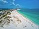 Aerial shot overlooking a beautiful beach with clear blue and green waters, city buildings, and sugar white sand at 113 Fillmore Dr, Sarasota, FL 34236
