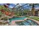Gorgeous pool and hot tub with tropical plants and rock waterfall feature within screened enclosure at 113 Fillmore Dr, Sarasota, FL 34236