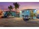 Well-maintained apartment building with ample parking featuring a turquoise exterior and palm tree landscaping at 117 7Th N St # 35, Bradenton Beach, FL 34217