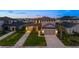 Charming two-story home featuring a manicured lawn and a three-car garage with individual doors at twilight at 16626 Paynes Mill Dr, Lakewood Ranch, FL 34211