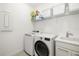 Clean and organized laundry room with modern washer, dryer, sink, and ample shelving for storage at 16626 Paynes Mill Dr, Lakewood Ranch, FL 34211