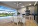 The outdoor kitchen includes a built-in grill, stainless steel appliances, and scenic views of pool, patio, and lake at 16626 Paynes Mill Dr, Lakewood Ranch, FL 34211