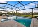 A large screened-in pool and spa with travertine pavers, overlooking manicured lawn at 16626 Paynes Mill Dr, Lakewood Ranch, FL 34211
