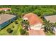 Aerial view showing the tile roof of the home with a manicured lawn, tropical landscaping and a brick driveway at 21287 Sandal Foot Dr, Venice, FL 34293