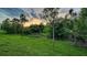 Expansive green backyard featuring lush landscaping and picturesque natural views with sunset sky at 21287 Sandal Foot Dr, Venice, FL 34293
