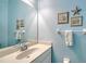 Bright bathroom with blue walls, framed artwork, decorative starfish, and white vanity at 21287 Sandal Foot Dr, Venice, FL 34293