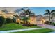 Well-maintained home exterior featuring a lush lawn, tropical landscaping, brick walkway and a two-car garage at 21287 Sandal Foot Dr, Venice, FL 34293