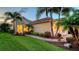 Charming exterior view of home showcasing manicured lawn, brick walkway, tropical landscaping, and attached garage at 21287 Sandal Foot Dr, Venice, FL 34293