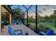 Relax on this screened patio featuring brick pavers, comfortable chairs, and picturesque scenery at 21287 Sandal Foot Dr, Venice, FL 34293