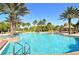 Community pool featuring clear blue water surrounded by lounge chairs and palm trees at 2212 Weaver Bird Ln, Venice, FL 34292