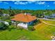 Low aerial view of a single story home, with lush green landscaping, with a sunny sky background at 2305 Riverview Blvd, Bradenton, FL 34205