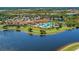 An aerial shot of a clubhouse, resort-style pool, and tropical landscaping overlooking a serene lake at 23261 Banbury Way # 501, Venice, FL 34293