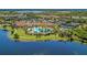 Aerial view showcasing a community pool, tennis courts, palm trees, and lush landscaping next to a shimmering lake at 23261 Banbury Way # 501, Venice, FL 34293
