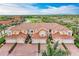 Aerial view of townhomes with red tile roofs, garages, and landscaping in a lakeside community at 23261 Banbury Way # 501, Venice, FL 34293