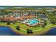 A bird's eye view of a clubhouse, lush tropical landscaping, tennis courts, and shimmering lake at 23261 Banbury Way # 501, Venice, FL 34293