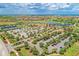 An aerial view of a lush community with a clubhouse, parking area, and tennis courts near a golf course at 23261 Banbury Way # 501, Venice, FL 34293