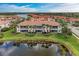 Aerial view of condo building with tiled roof near a scenic pond at 23261 Banbury Way # 501, Venice, FL 34293