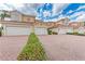 Townhome exterior with multiple garage doors, tile roofs, and well-maintained brick paved driveway at 23261 Banbury Way # 501, Venice, FL 34293