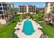 An aerial view of a pool featuring lounge chairs, lush landscaping, and a neighboring condominium building at 2333 Gulf Of Mexico Dr # 1A2, Longboat Key, FL 34228