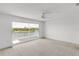 Bedroom with a sliding glass door to the balcony showcasing panoramic waterfront views and neutral carpeting at 2435 E Del Webb Blvd, Sun City Center, FL 33573