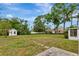 Spacious backyard with a well-manicured lawn, lush trees, and a detached shed at 320 25Th W St, Bradenton, FL 34205