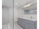 Modern bathroom with double vanity, large mirror, and glass enclosed shower with white tiling at 3356 Maiden Ln, Sarasota, FL 34231