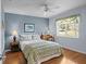 Cozy bedroom featuring hardwood floors, blue accent wall, and bright window at 3859 Little Country Rd, Parrish, FL 34219