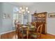 Bright dining room with natural light, chandelier, seating for six, hardwood floors, and a view to a manicured lawn at 3859 Little Country Rd, Parrish, FL 34219