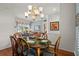 Bright dining room with chandelier, seating for six, hardwood floors, and views into the adjacent living area at 3859 Little Country Rd, Parrish, FL 34219