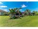 A lush green backyard featuring a screened-in pool, manicured tropical foliage and lawn at 4607 Benito Ct, Bradenton, FL 34211